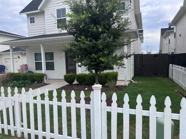 a front view of white house with a fence