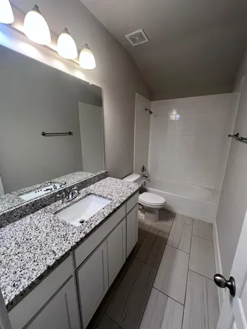 a bathroom with a granite countertop sink a toilet and a large mirror