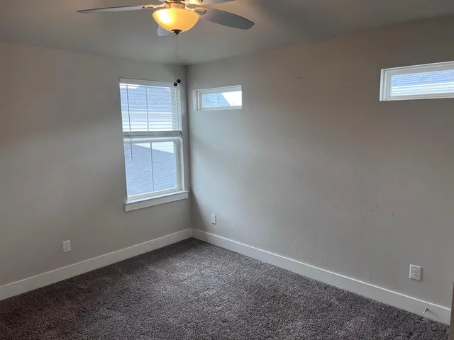 an empty room with windows and fan