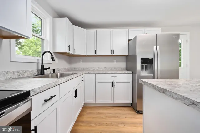a kitchen with granite countertop a sink stainless steel appliances and window