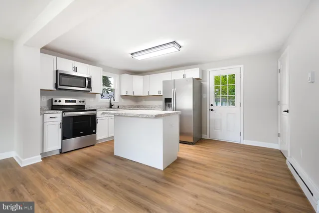 a kitchen with granite countertop a refrigerator oven a sink dishwasher and a stove with wooden floor