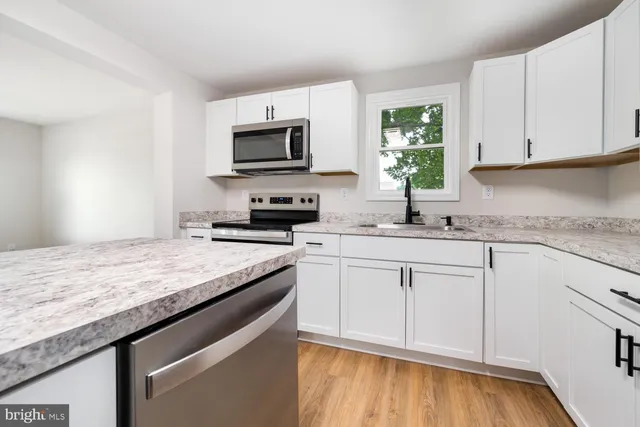 a kitchen with granite countertop a sink white cabinets and a stove