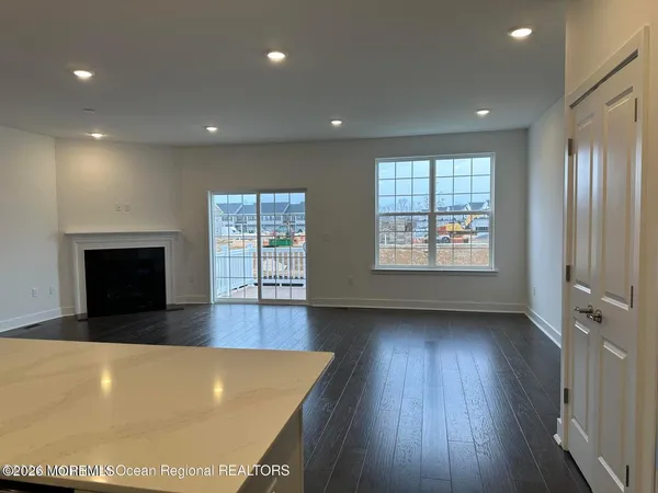 a view of an empty room with wooden floor and a fireplace