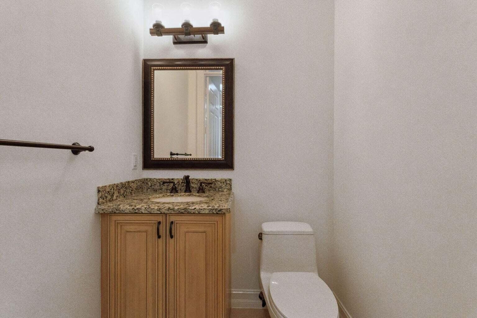 3873 Northeast 22nd Way Lighthouse Point, FL 33064 - Photo 41 of 43 a bathroom with a toilet sink and mirror