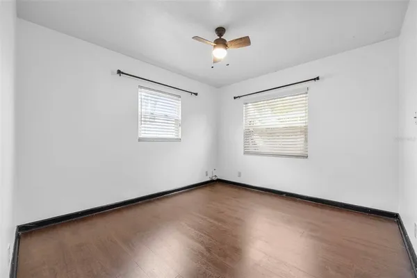 an empty room with wooden floor and ceiling fan