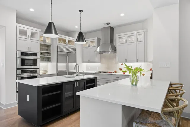 a kitchen with stainless steel appliances a sink a stove a chimney a kitchen island and chairs
