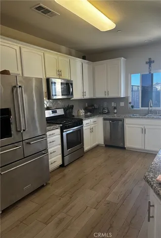 a kitchen with stainless steel appliances granite countertop a stove top oven a sink and a refrigerator