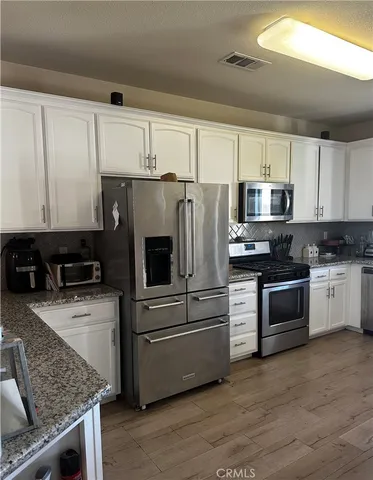 a kitchen with granite countertop a refrigerator stove and microwave