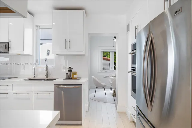 a kitchen with stainless steel appliances a refrigerator sink and white cabinets