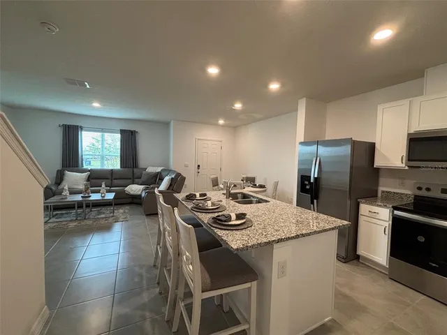 a kitchen with sink refrigerator and chairs