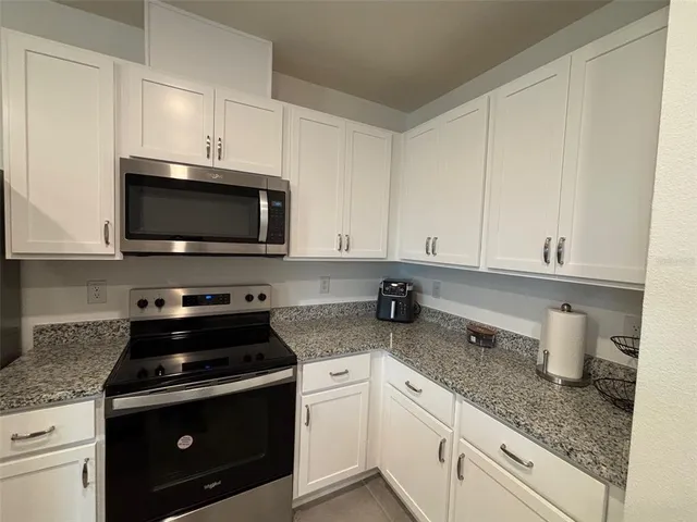 a kitchen with granite countertop white cabinets and appliances