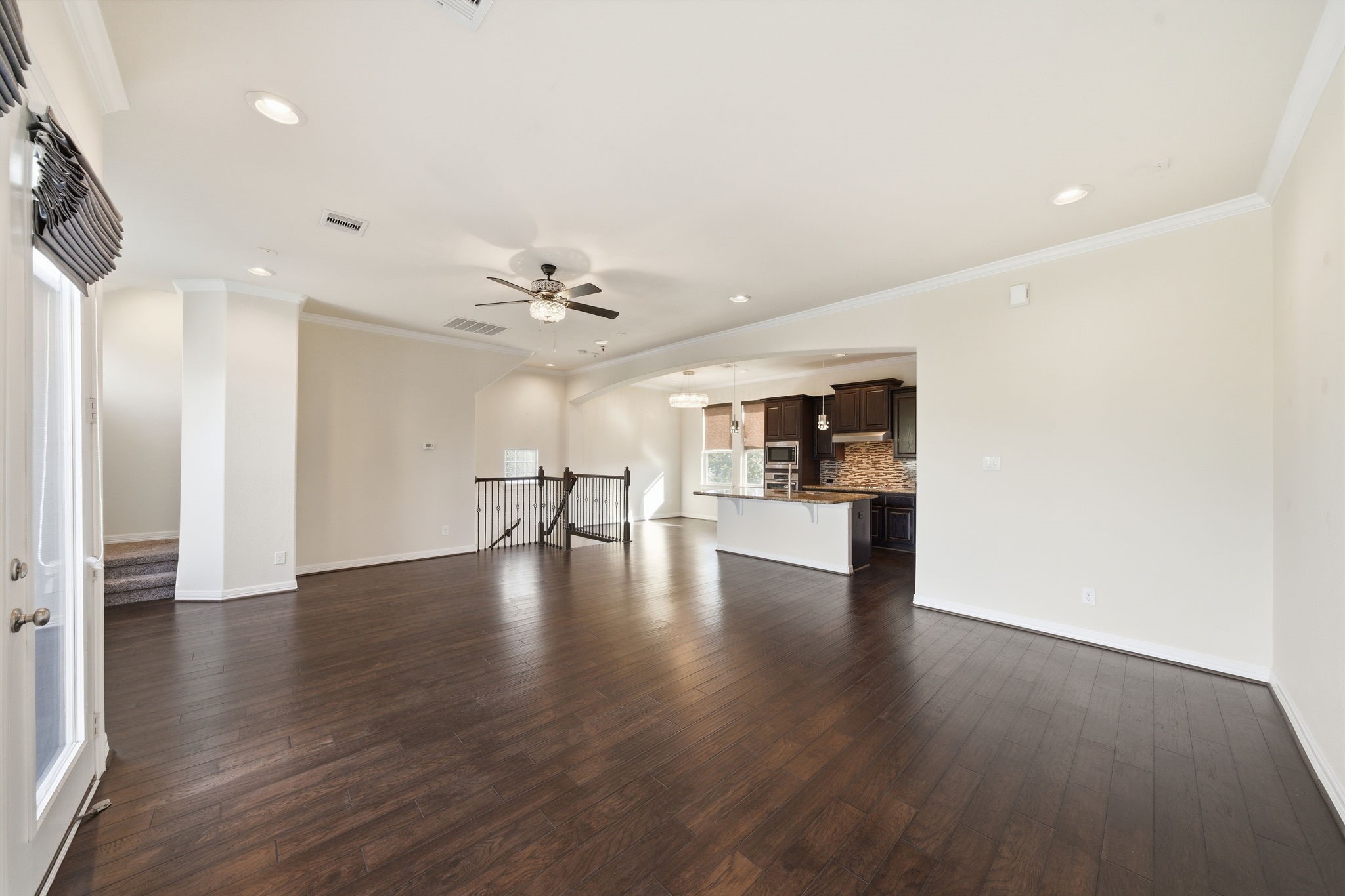 10218 Spring Shadows Park Circle Houston, TX 77080 - Photo 23 of 46 a view of an empty room with wooden floor and a kitchen