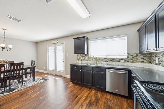 a kitchen with stainless steel appliances granite countertop hardwood floor sink stove dining table and chairs