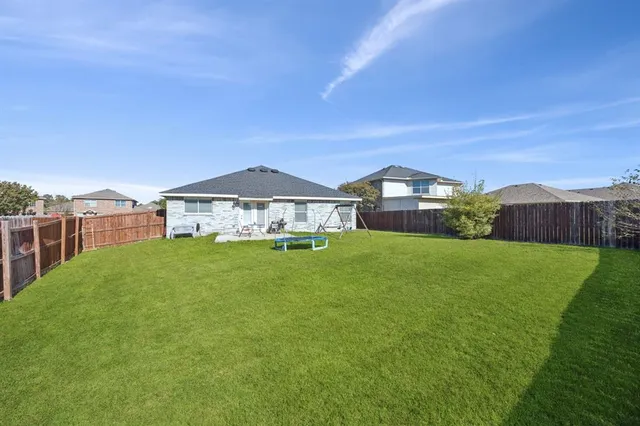 a view of an house with a big yard plants and large trees
