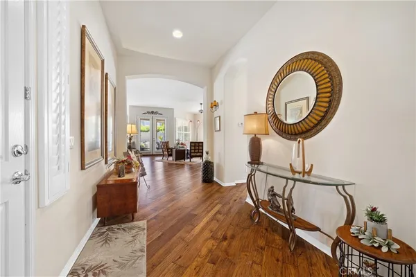 a living room with furniture a mirror and a wooden floor