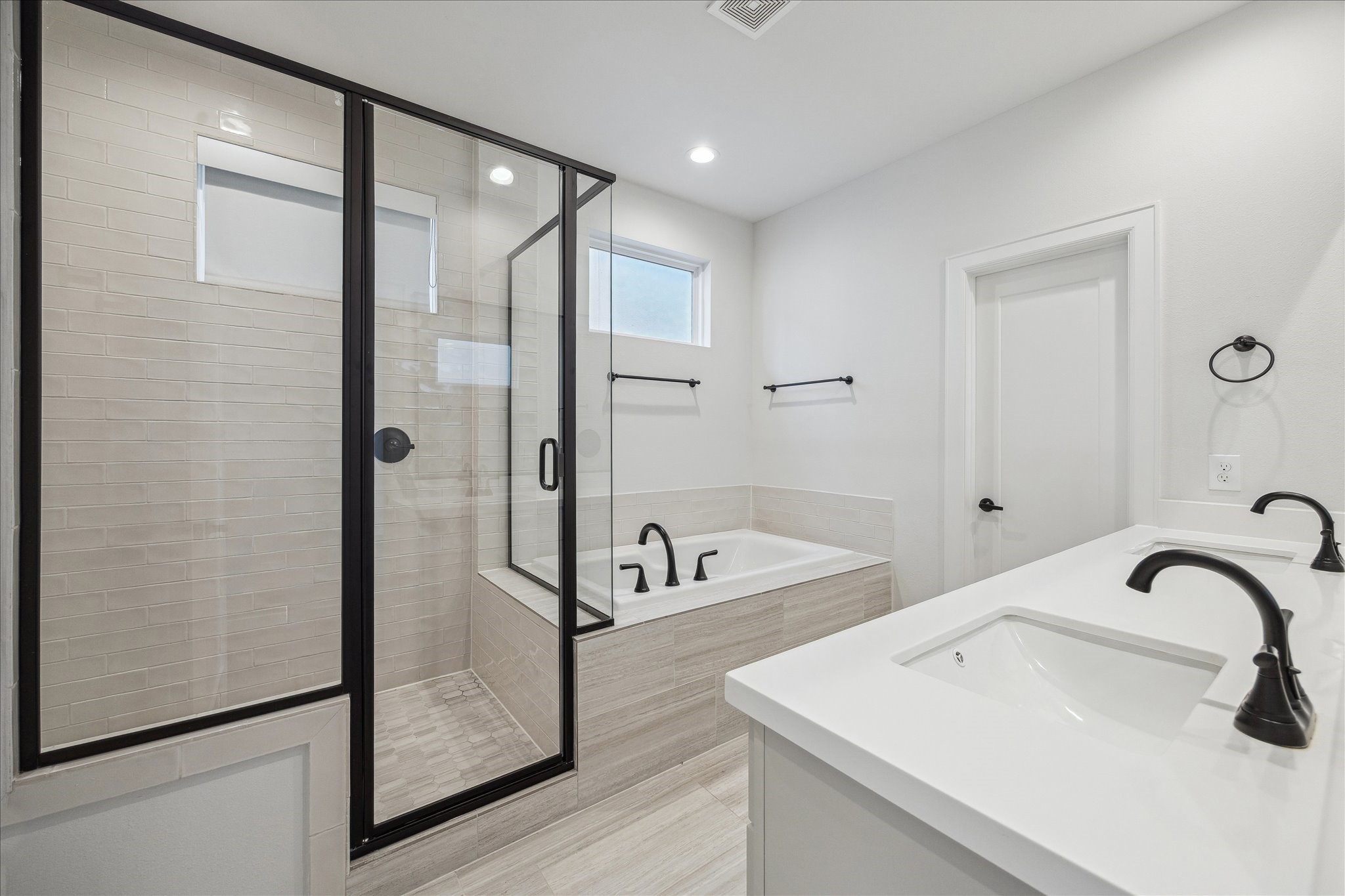 1603 Patterson Street, Unit E Houston, TX 77007 - Photo 28 of 32 This modern bathroom features a spacious glass-enclosed shower, a large soaking tub, and a double vanity with sleek black fixtures, offering a clean and contemporary look.