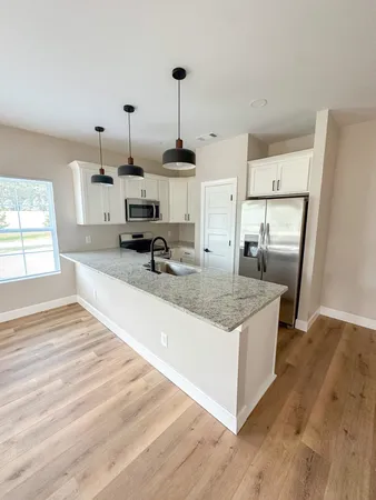 a kitchen with stainless steel appliances granite countertop a sink a stove and a wooden floors
