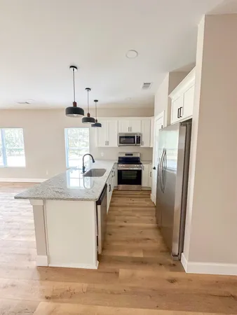 a kitchen with stainless steel appliances granite countertop a refrigerator a stove and a sink with wooden floor