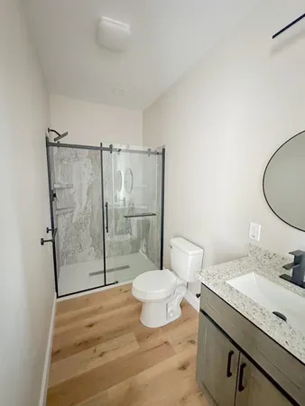 a bathroom with a granite countertop sink toilet a mirror and shower