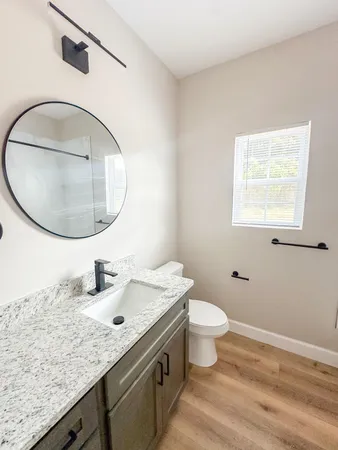 a bathroom with a granite countertop toilet a sink and a mirror
