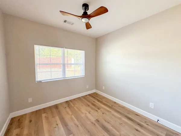 a view of empty room with wooden floor and fan