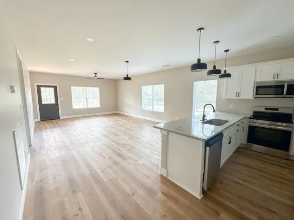 a kitchen with kitchen island granite countertop a sink cabinets and wooden floor