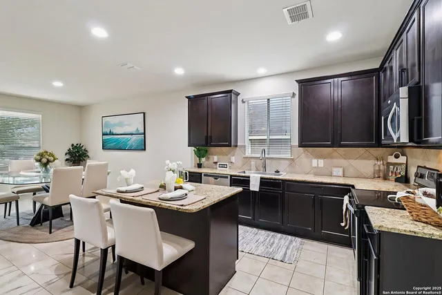 a kitchen with a sink a stove a refrigerator and chairs
