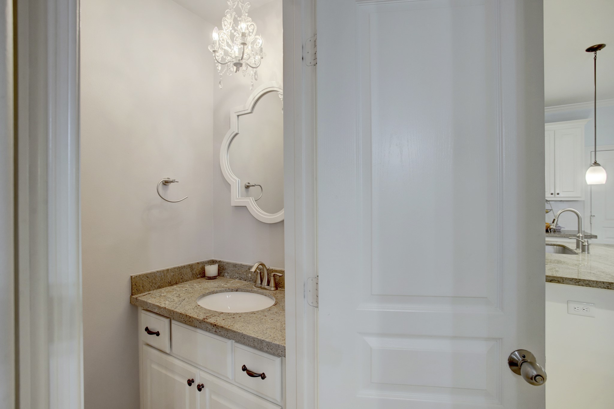 4230 Drake Street Houston, TX 77005 - Photo 13 of 38 Powder Room - The powder room features a vanity with a granite countertop, a mirror with a scalloped frame, a Victorian-style chandelier and stainless-steel hardware.