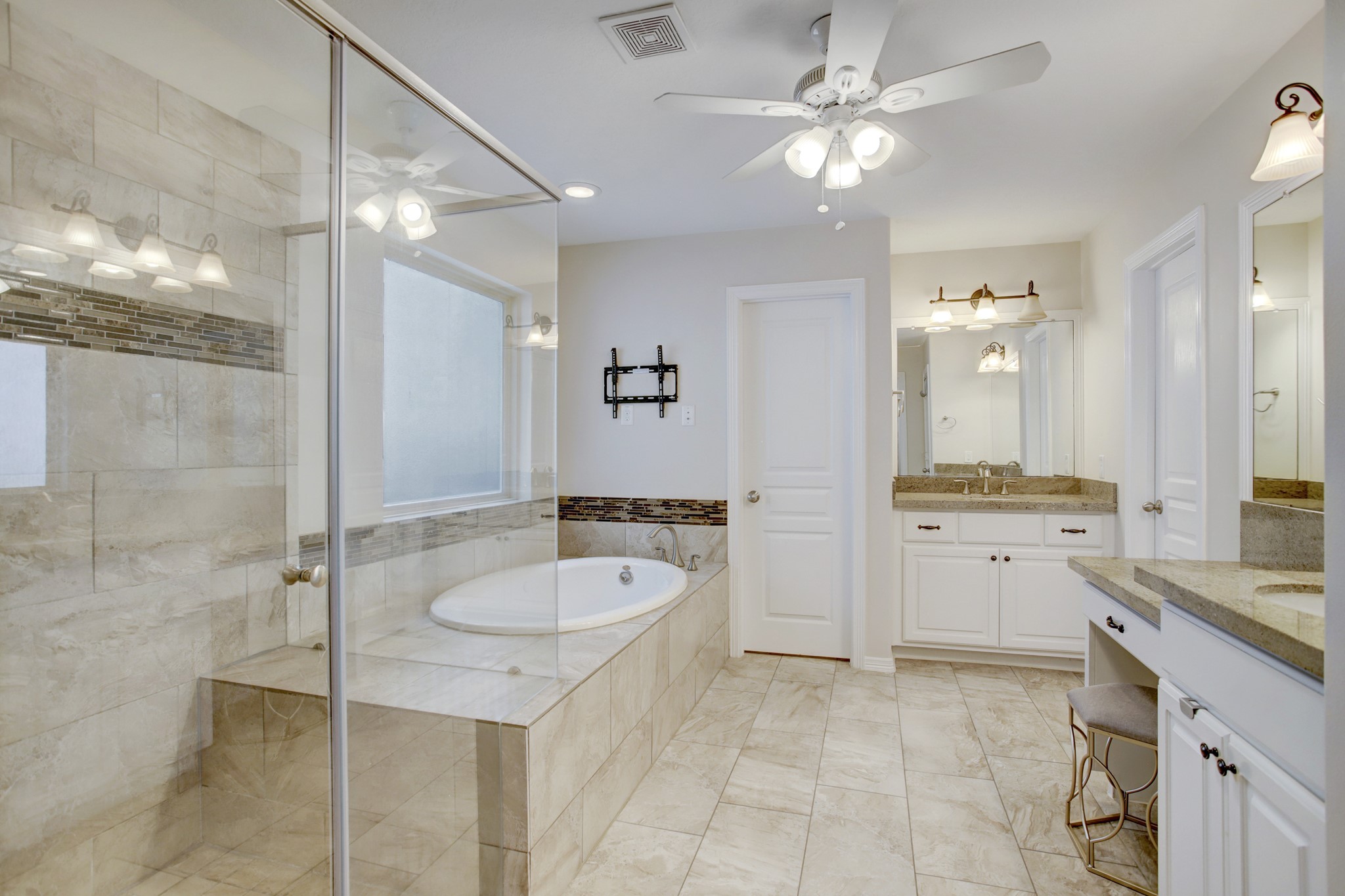 4230 Drake Street Houston, TX 77005 - Photo 17 of 38 Primary Suite Bathroom - Crisp and clean, the primary bathroom features dual sinks, a vanity, a fully-tiled shower, a jetted spa tub, a linen closet with deep shelves (not shown), a separate water closet (door straight ahead) and a spacious closet (door on the right).