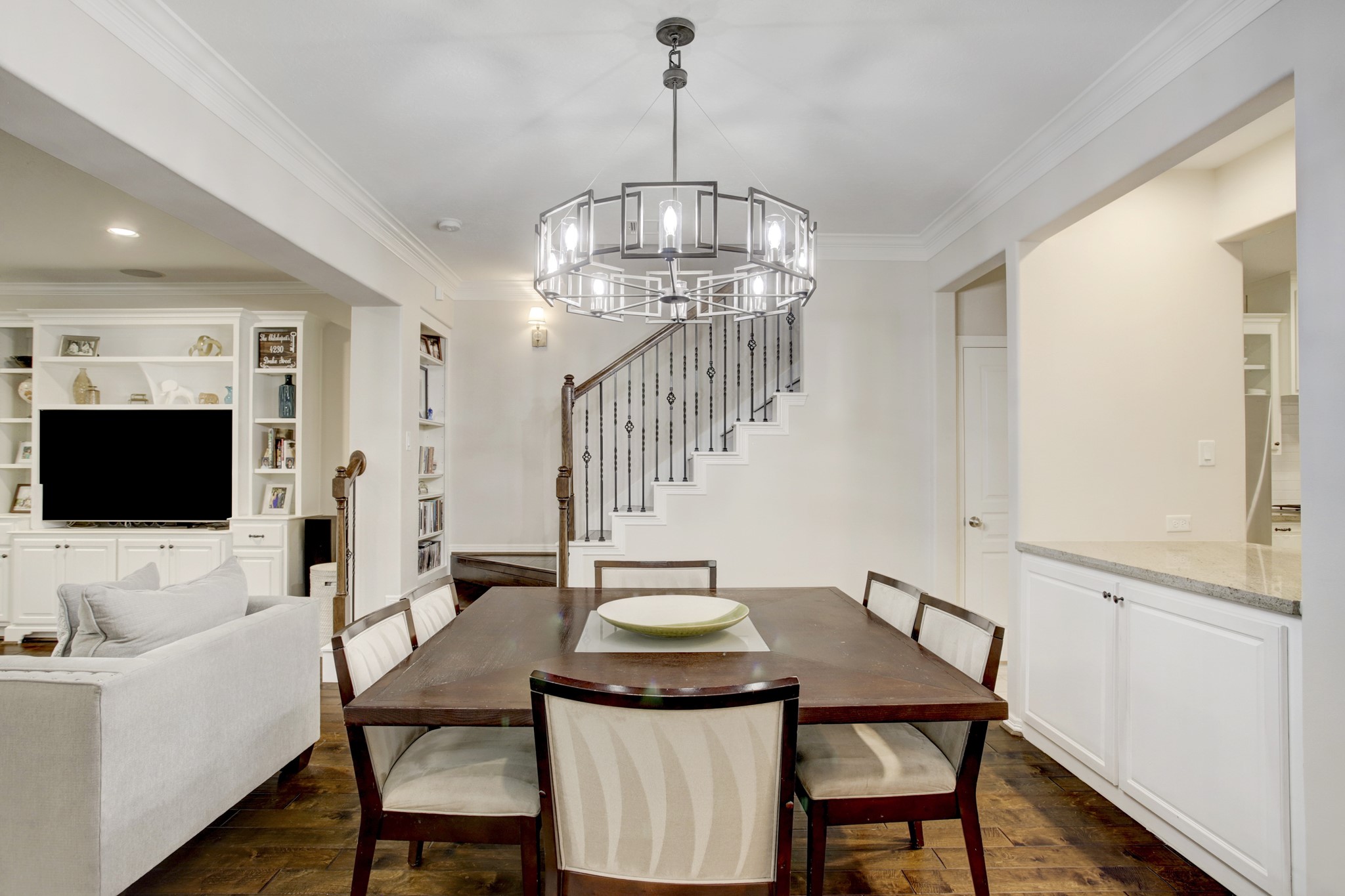 4230 Drake Street Houston, TX 77005 - Photo 5 of 38 Dining Room – Cozy and elegant, the dining area can comfortably accommodate an eight-person table. The designer chandelier is a statement piece that offers an element of opulence and the wrought iron balustrade serves as a beautiful backdrop.