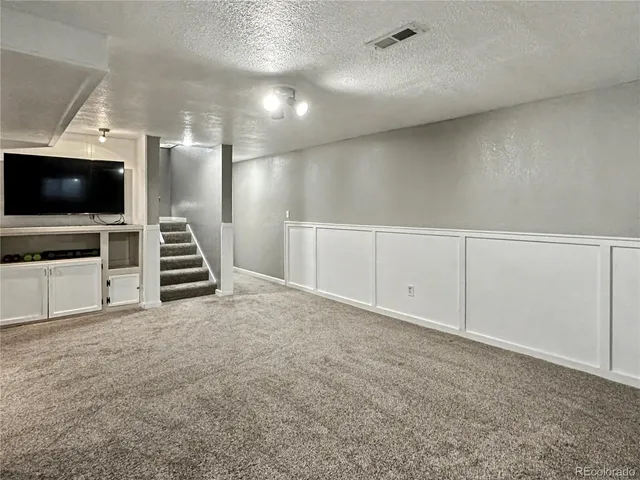 a view of an empty room with stairs a fireplace and windows