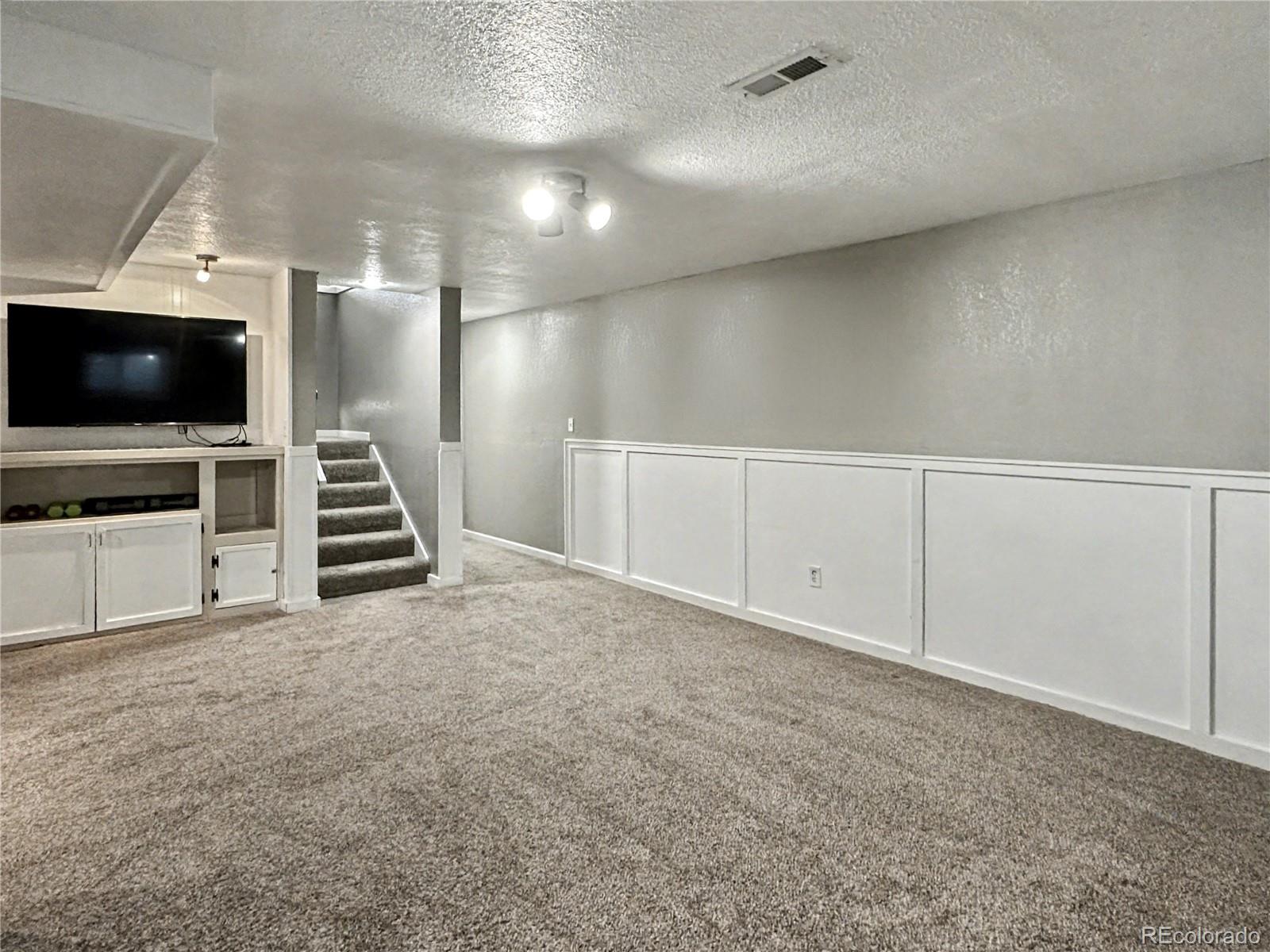 804 Nicole Road Sterling, CO 80751 - Photo 18 of 24 a view of an empty room with stairs a fireplace and windows
