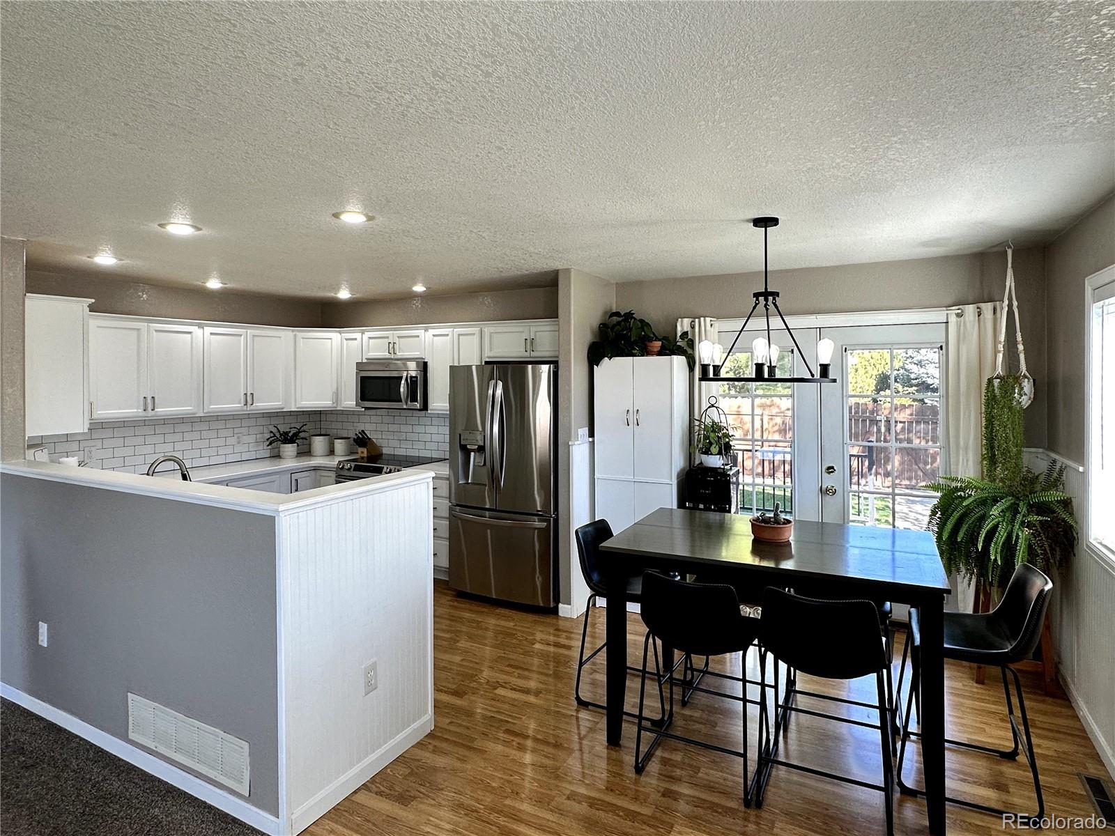 804 Nicole Road Sterling, CO 80751 - Photo 3 of 24 a kitchen with stainless steel appliances kitchen island granite countertop a refrigerator a stove a microwave oven a dining table and chairs with wooden floor