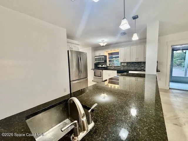 a kitchen with stainless steel appliances granite countertop a refrigerator a stove and a sink with wooden floor