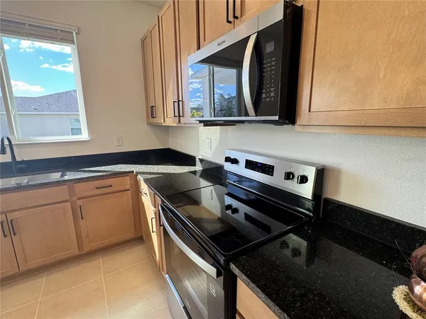 a kitchen with granite countertop a stove a sink and a microwave