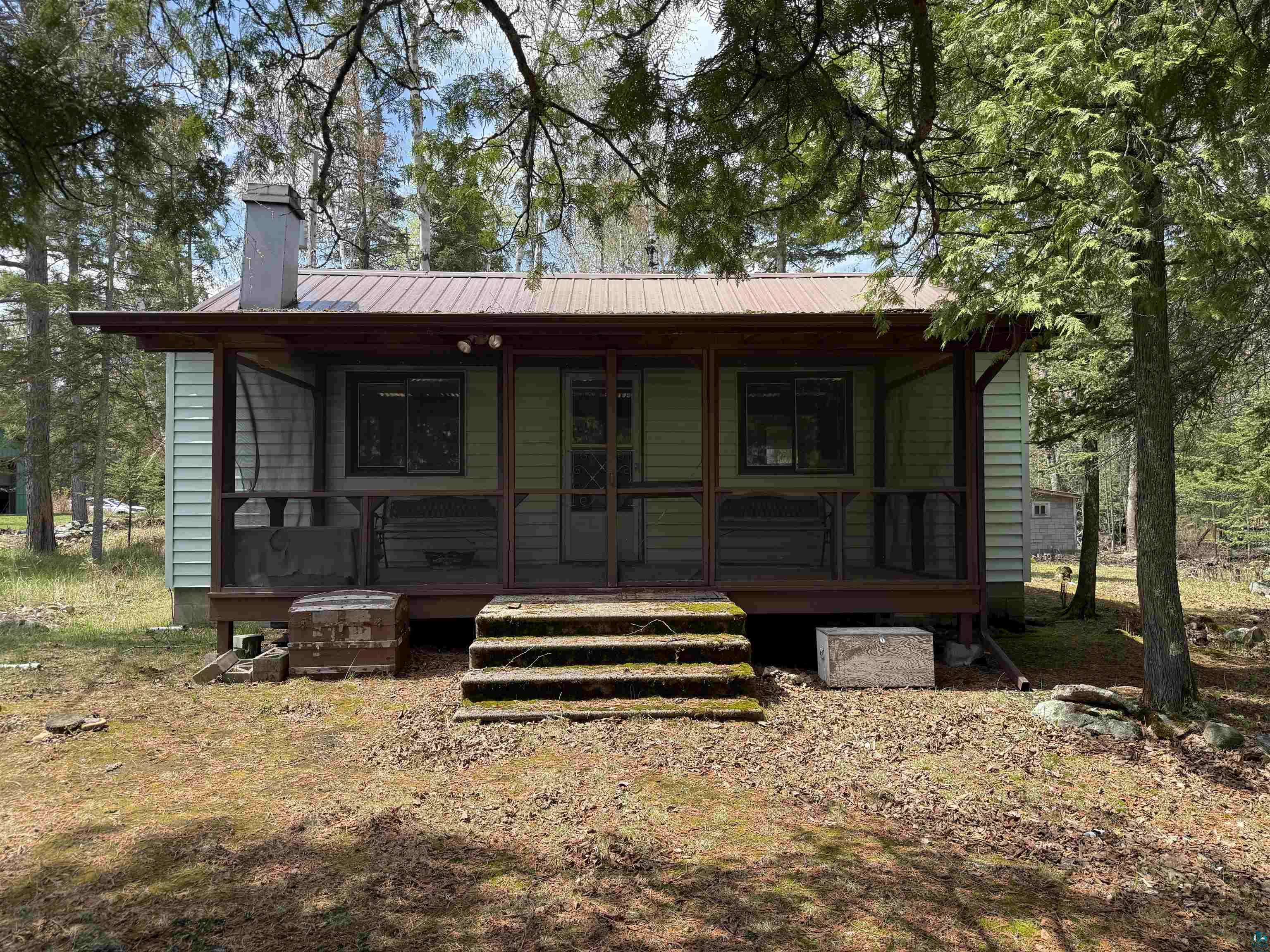 Exterior featuring light green horizontal vinyl siding and a brown metal roof. Screen porch with a view of the lake.