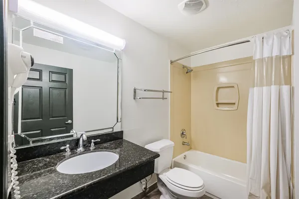 a bathroom with a granite countertop sink toilet tub and shower