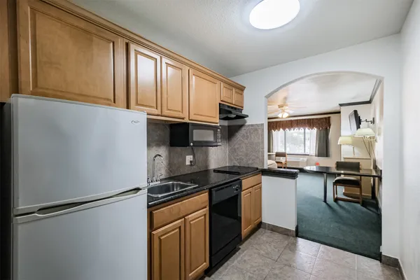 a kitchen with granite countertop a refrigerator a sink a stove and cabinets