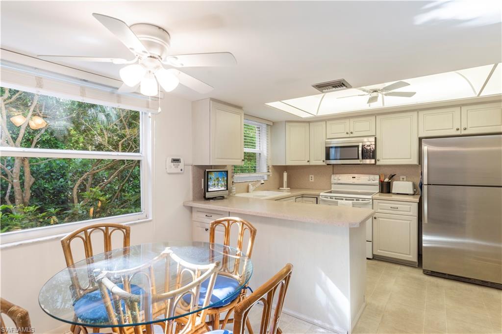 3200 Binnacle Drive, Unit C1 Naples, FL 34103 - Photo 8 of 37 a kitchen with stainless steel appliances granite countertop a stove a refrigerator a kitchen island a stove a dining table and chairs with wooden floor