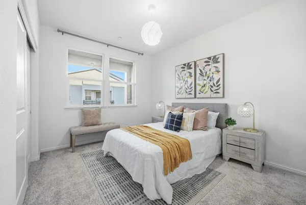 a bedroom with bed and a large mirror next to a window