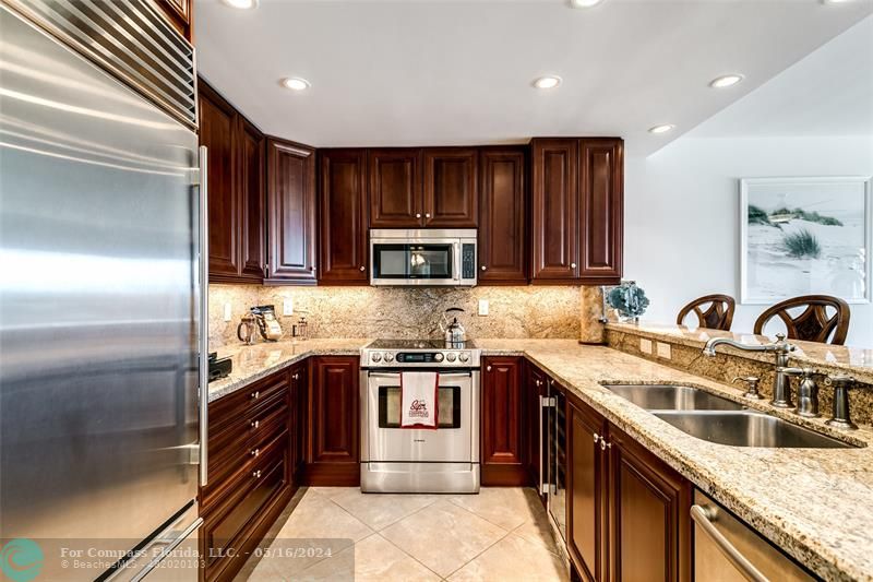 a kitchen with stainless steel appliances granite countertop a sink stove cabinets and refrigerator