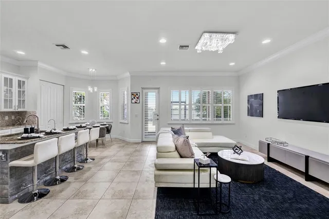 a living room with furniture a flat screen tv and kitchen view