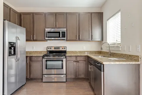 a kitchen with granite countertop a sink stove and refrigerator