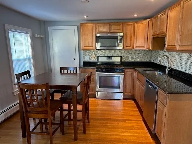 a kitchen with stainless steel appliances wooden cabinets dining table and chairs