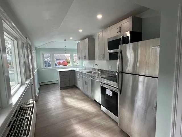 a kitchen with stainless steel appliances a refrigerator a sink a stove top oven and cabinets