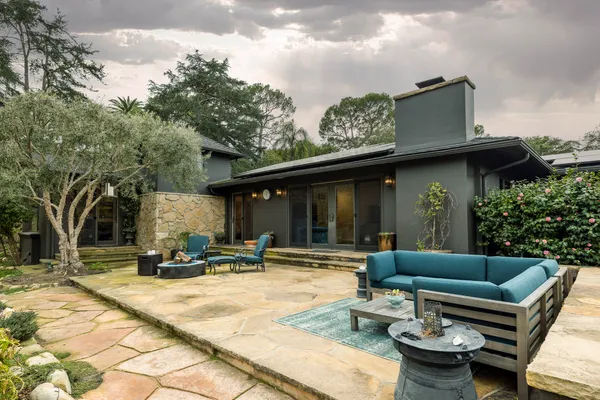 a view of a patio with couches table and chairs with wooden fence