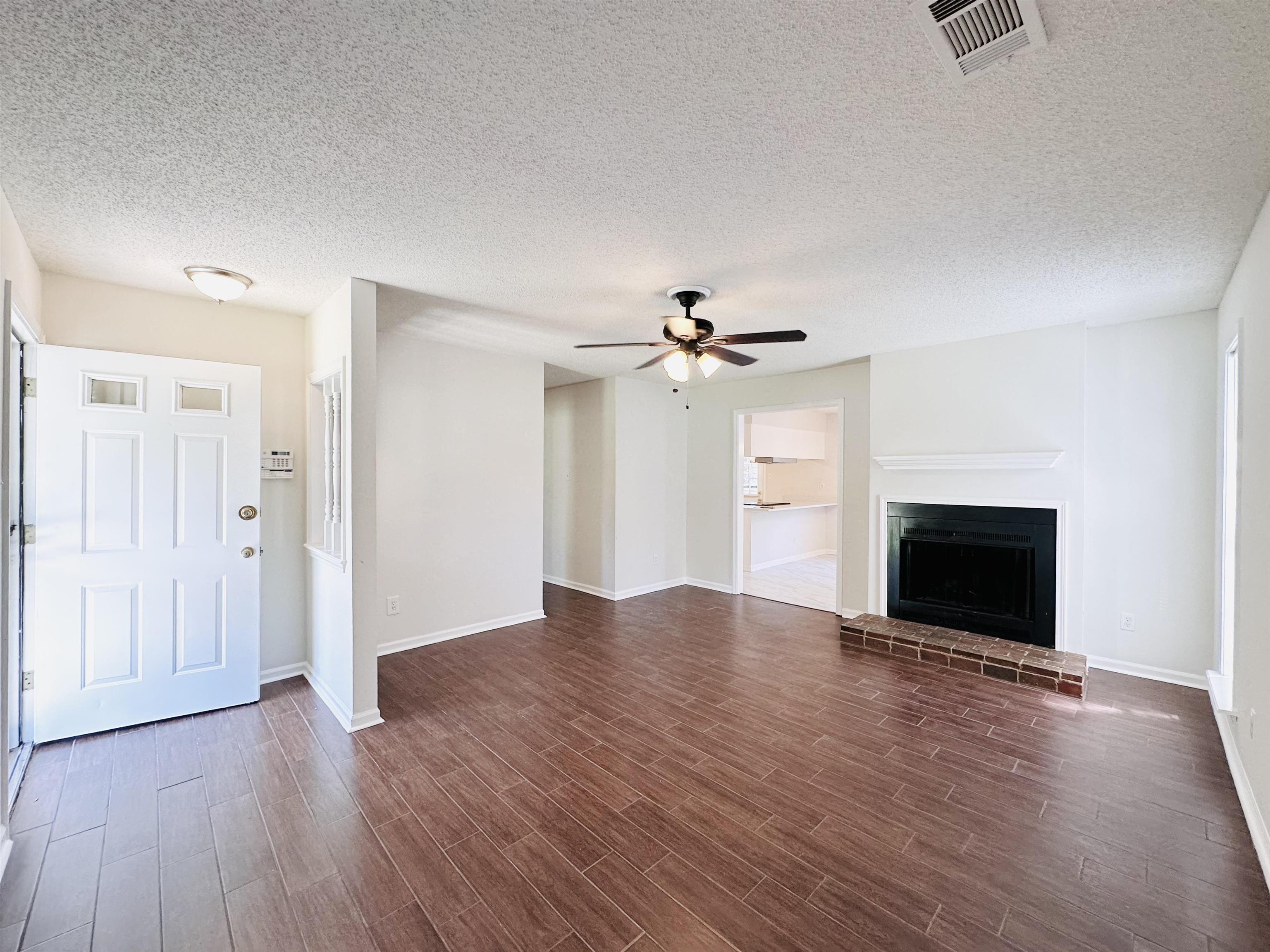 4192 Riche Road Memphis, TN 38128 - Photo 3 of 32 an empty room with wooden floor fireplace and ceiling fan