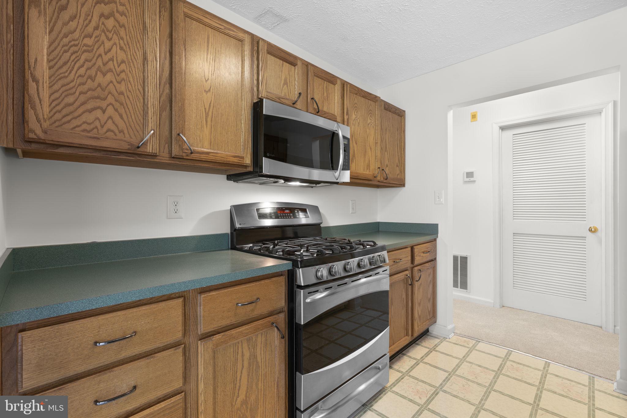 2444 Blue Spring Court, Unit 203 Odenton, MD 21113 - Photo 12 of 36 a kitchen with stainless steel appliances granite countertop a stove a microwave and cabinets