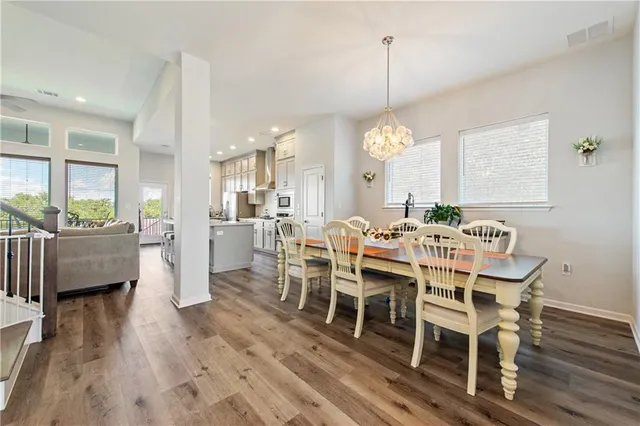 a dining room with wooden floor a chandelier a glass table and chairs