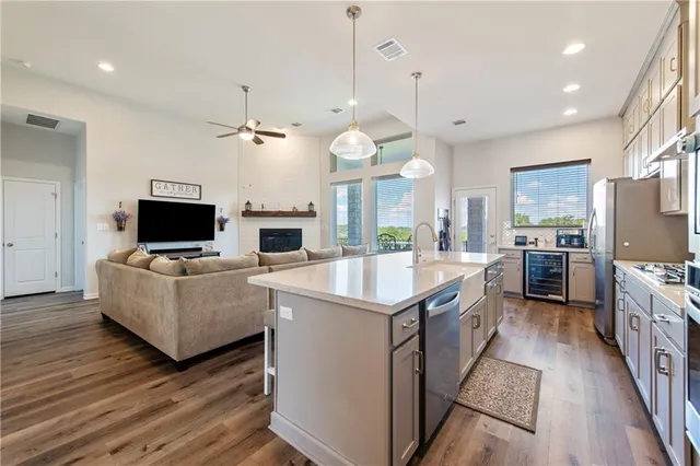 a large kitchen with kitchen island a living room a wooden floor and a view of living room